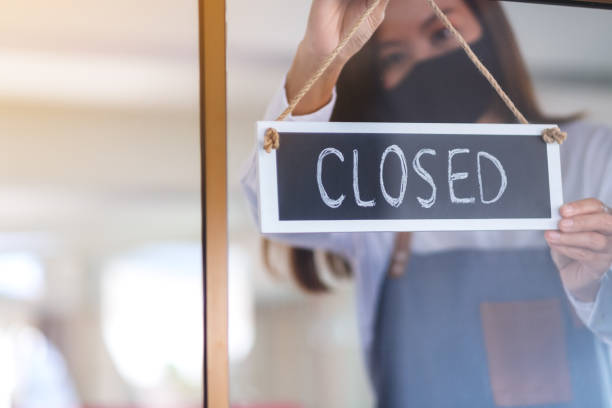 istock A waitress wearing protective face mask hanging closed sign on front door 1296789044