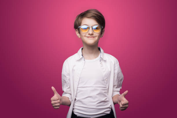 istock Confident boy with glasses is gesturing the like sign on a red studio wall 1296795951