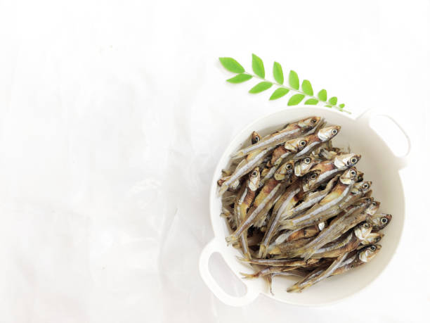 Dried Anchovy Fish decorated with herbs and lemons on a White Background,Selective Focus.