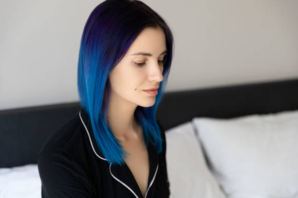 piękna kobieta z niebieskimi włosami w czarnej koszuli nocnej siedzącej na łóżku po śnie - blue hair zdjęcia i obrazy z banku zdjęć