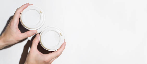 istock Male hands holding disposable cups with coffee on a white background, top view. Banner, copy space. Food delivery concept, coffee to go 1296797755