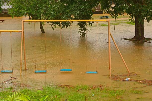istock Playground swings with flooded ground and grass underneath 1296799823