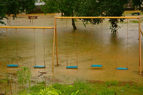 istock Playground swings with flooded ground and grass underneath 1296800386