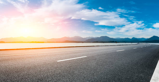 Asphalt road and mountain with sky clouds at sunset. Empty asphalt road and mountain with sky clouds at sunset. west lake stock pictures, royalty-free photos & images