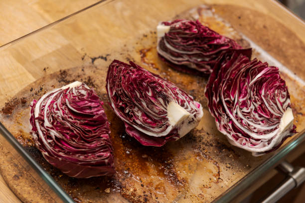 radicchio en quart dans le plat en verre de casserole sur la table en bois de cuisine - radicchio photos et images de collection