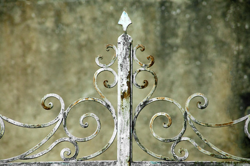 Detail of old rusty cast iron gate, white paint peeling off. Entrance to an old garden and mansion. Galicia, Spain.