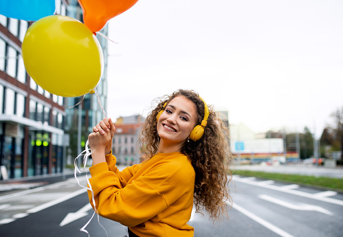 Young woman with balloons outdoors on street, video for social media concept.