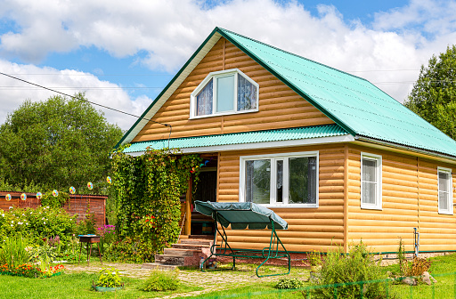 Borovichi, Russia - August 14, 2020: Cozy wooden country house with outbuildings and beautiful decorative flowers. Summer cottage in sunny day