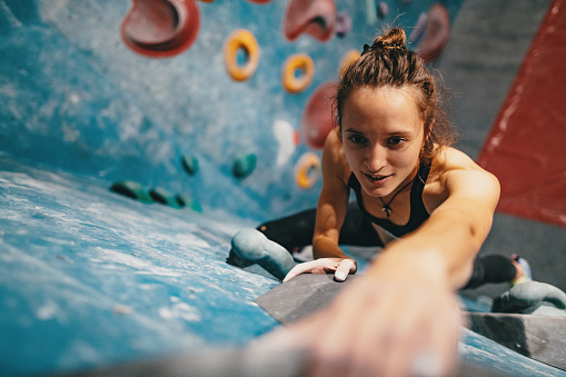 High angle view of skinny strong woman climbing on boulder wall