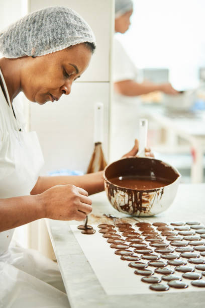 istock Chocolate factory worker pouring melted chocolate onto a baking sheet 1296811080