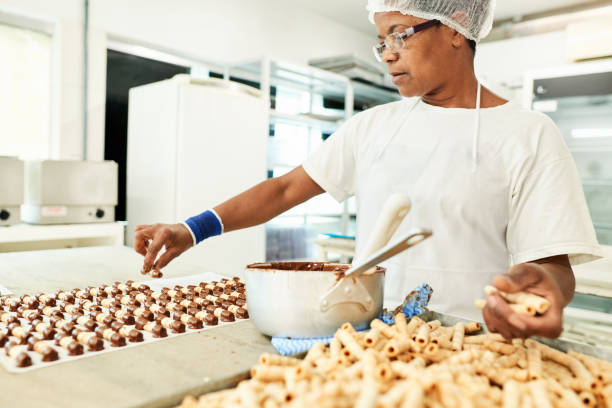 istock Confectioner dipping wafer sticks in melted chocolate 1296811197