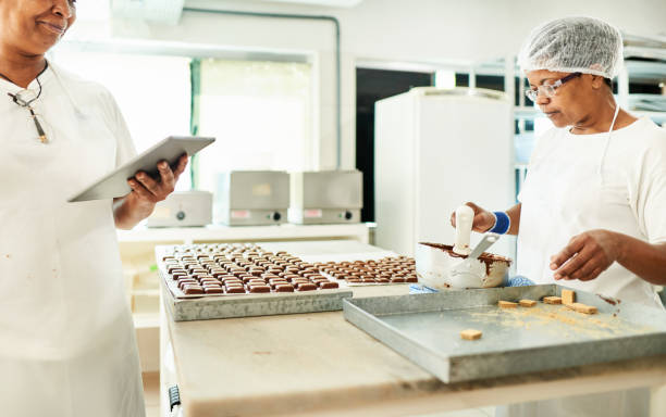 istock Two confectioners working at a table in a chocolate production factory 1296811833