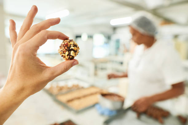 trabajador de fábrica de chocolate sosteniendo una confitería en la mano - food industry manufacturing human hand fotografías e imágenes de stock