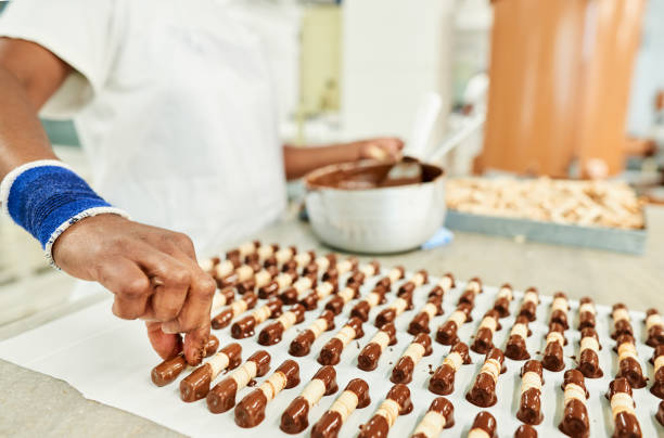 istock Confectioner placing chocolate dipping wafer sticks on baking paper 1296811931