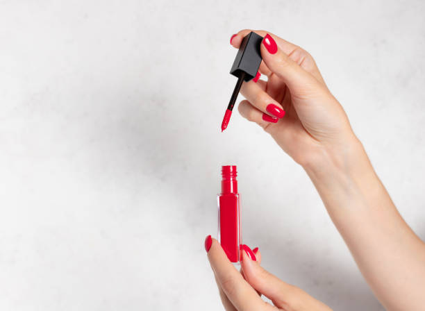 istock female hands with red nails opening red liquid lipstick 1296812212