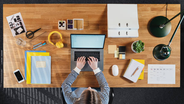istock Top view of female student working on computer at desk at home. 1296812345
