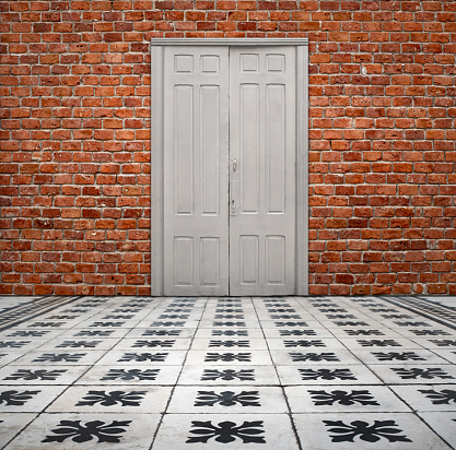 Brick wall background and antique floor tiles with closed white door