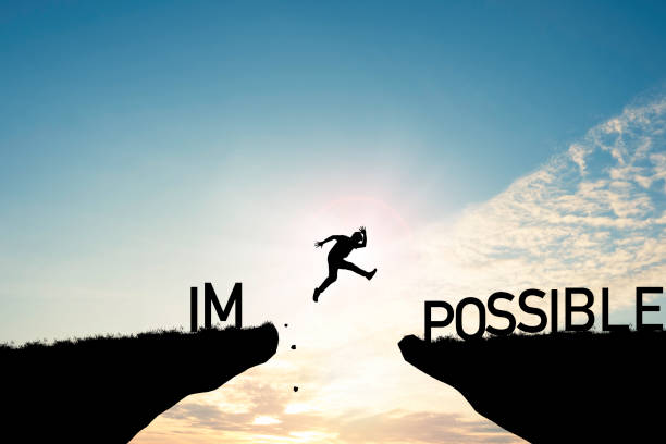 istock Mindset concept ,Silhouette man jumping over impossible and possible  wording on cliff with cloud sky and sunlight. 1296816255