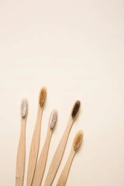 Photo of Top view of bamboo toothbrushes arranged on cream background