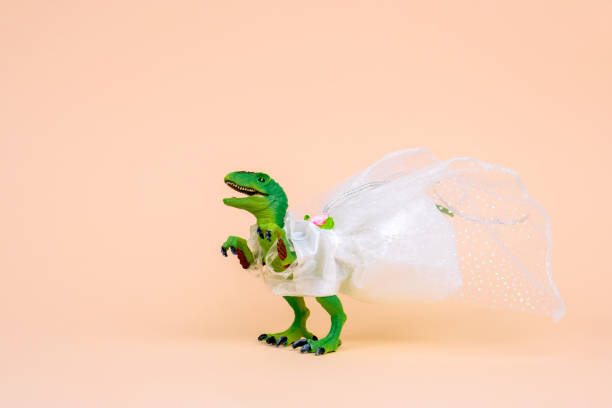 파스텔 배경에 흰색 웨딩 드레스를 입고 귀여운 녹색 장난감 공룡. - 웨딩 드레스를 뉴스 사진 이미지