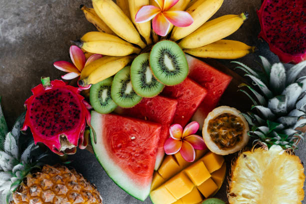 Tropical fruits assortment on a wooden plate. Stone background. Tropical fruits assortment on a wooden plate. Stone background. Top view. Copy space. dragon fruit flower stock pictures, royalty-free photos & images