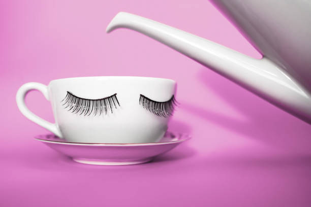 istock White coffee cup with eyelashes and teapot on a pink background. 1296822570