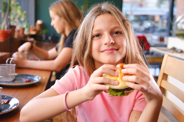 Three beautiful girls eating hamburgers in fast food restaurant