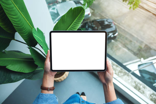 a woman holding digital tablet with blank white desktop screen stock photo
