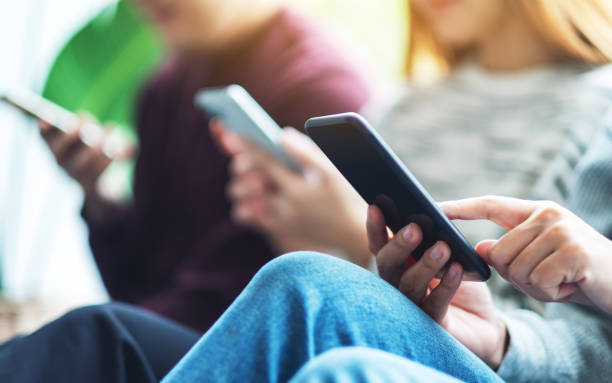 istock Group of young people using and looking at mobile phone while sitting together 1296823523