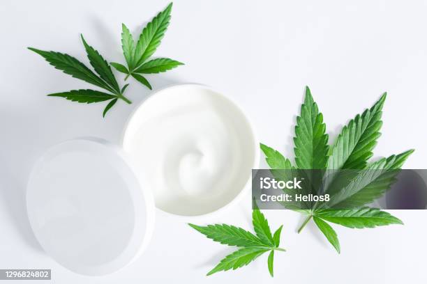 Green Cannabis Leaves With Jar Of Hemp Beauty Cream Lotion On White Backgroun Stock Photo - Download Image Now