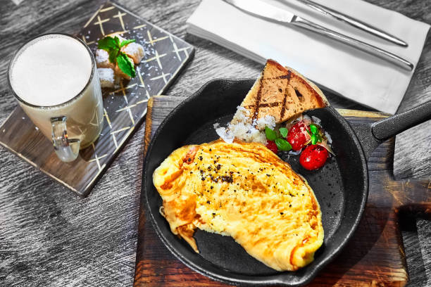 omelet with tomatoes and white onions in a black pan and a slice of rye bread. Healthy breakfast with your own hands. Delicious coffee with cane sugar stock photo