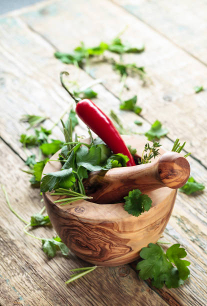istock Wooden mortar with pepper and herbs on an old wooden table. 1296830588