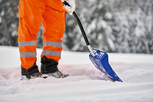 Snow removal, worker sweeps snow from road after winter storm Communal service worker in uniform with a shovel clears snow in winter winterdienst stock pictures, royalty-free photos & images