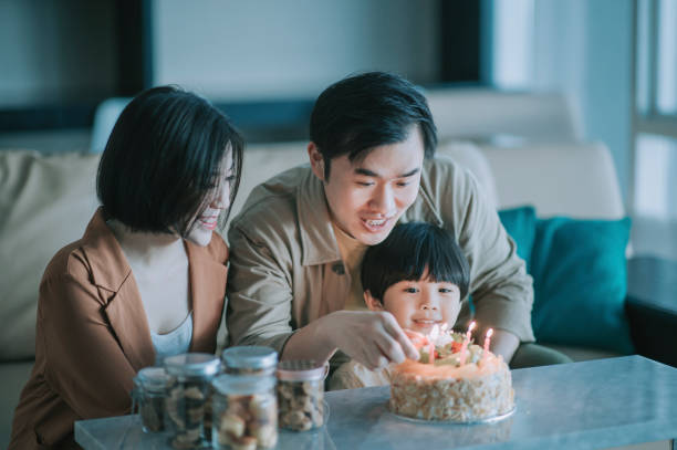 istock asian chinese father igniting birthday candle with lighter getting ready to sing birthday song for their son in living room celebrating birthday 1296833254
