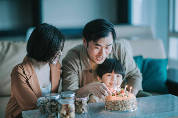 istock asian chinese father igniting birthday candle with lighter getting ready to sing birthday song for their son in living room celebrating birthday 1296833298
