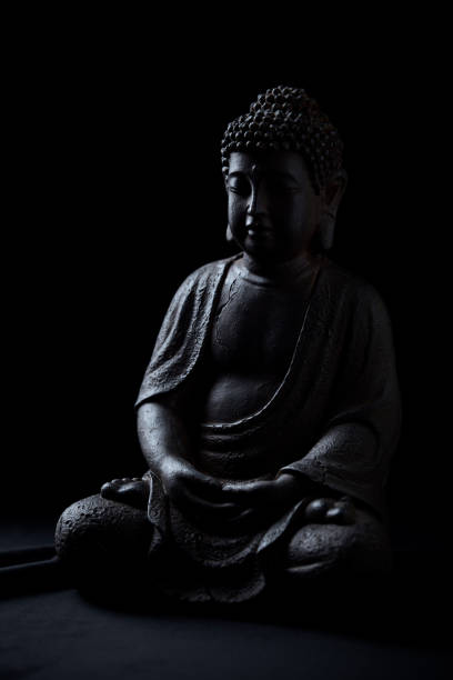istock Meditating Buddha Statue isolated on black background. Copy space. 1296834148