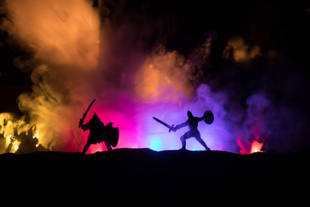 istock Medieval battle scene with cavalry and infantry. Silhouettes of figures as separate objects, fight between warriors on sunset foggy background. 1296837599