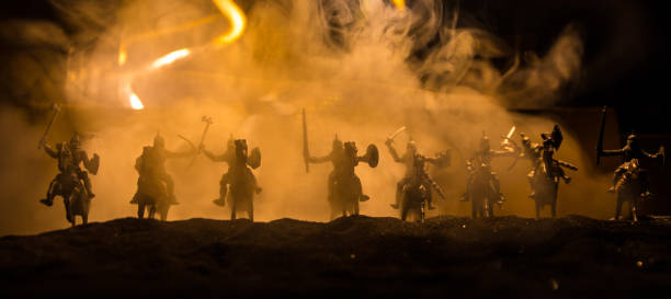 istock Medieval battle scene with cavalry and infantry. Silhouettes of figures as separate objects, fight between warriors on sunset foggy background. 1296837622