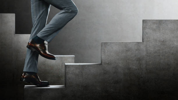 istock Motivation and challenging Concept. Steps Forward into a Success. Low Section of Businessman Walking Up on Staircase 1296837646