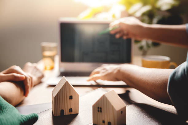 istock Buying a New House Concept. Real Estate Agent Explaining a Plan Design on Computer Laptop with Customer. Focus on House model 1296837679