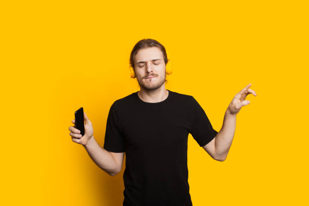 istock Long haired caucasian man with beard and black tshirt listening to musing using phone and headphones 1296838010