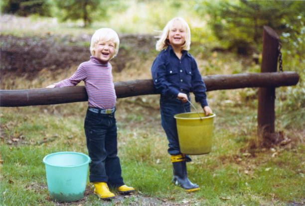 Vintage retro blackberry picking in a forest Vintage colorful 1979 image of a young boy and girl with blond hair picking blackberries in a forest. north rhine westphalia photos stock pictures, royalty-free photos & images