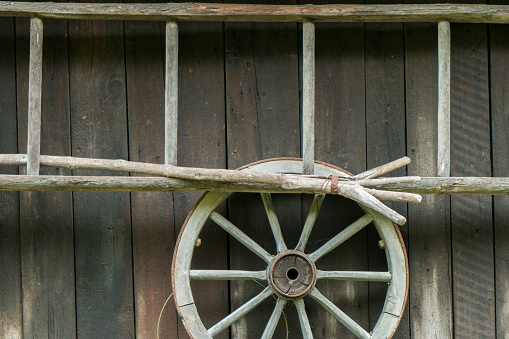 Ladder, wagon wheel and other equipment against a farm shed