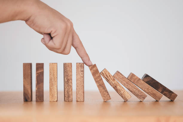 istock Stop crisis and risk management concept , Man using finger to stop wooden domino which falling to one wooden block still standing. 1296840920
