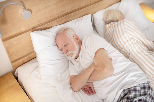 istock Aged married couple lying in bed back to back trying to fall asleep 1296844990