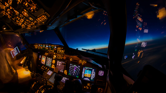 Flight deck and cockpit of a modern airliner in flight at dusk. Cruising on a beautiful colorful blue moonless sky at twilight