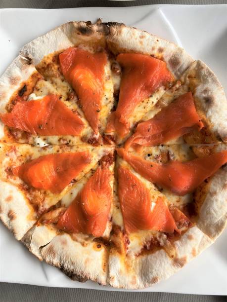 istock smoked salmon Pizza tomatoes and different spices on wooden table 1296845112