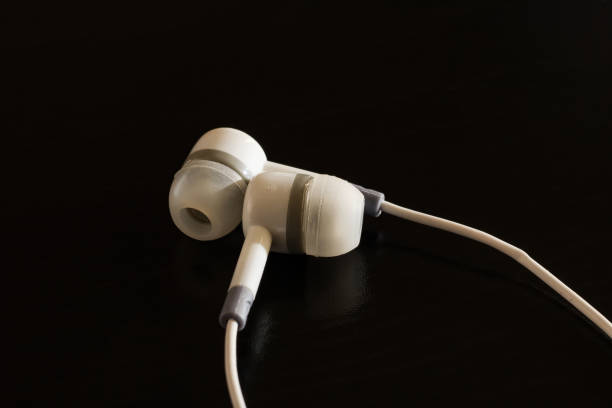 istock White headphones on a black wooden table 1296846686