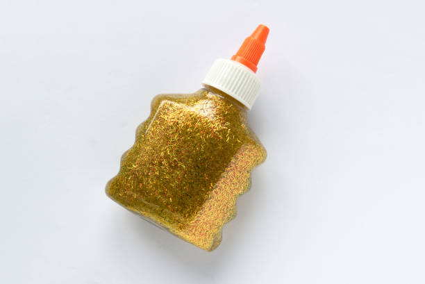 una botella de brillo dorado brillante pegamento sobre fondo blanco. - glue bottle isolated art and craft fotografías e imágenes de stock