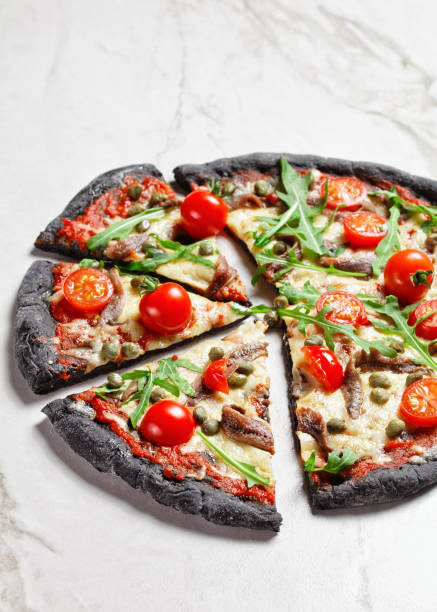 istock black dough pizza with jamon slices, mozzarella cheese, tomato, spinach leaves and red onion 1296847921